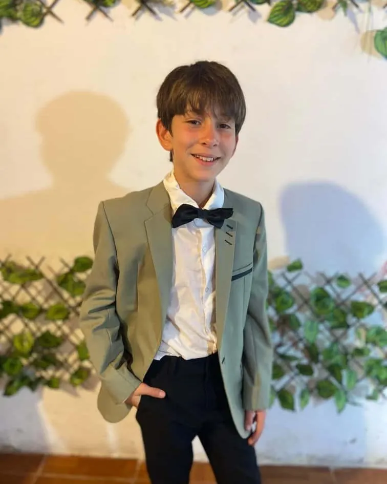 Niño con saco verde salvia y moño negro